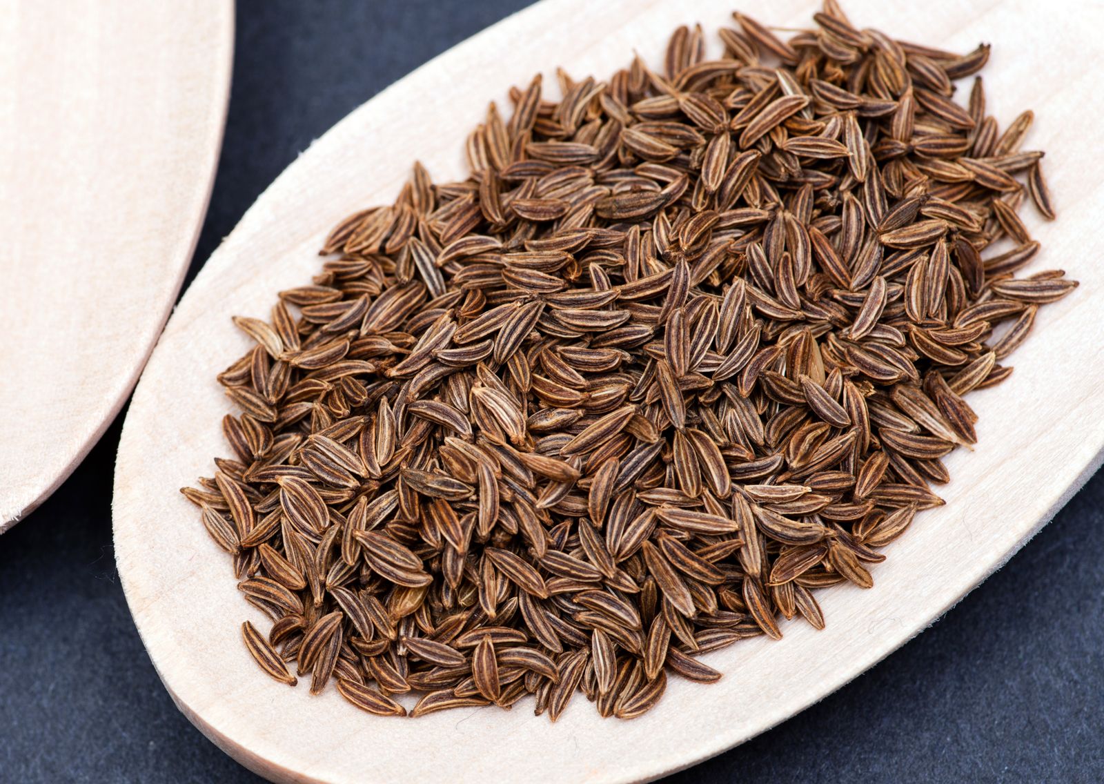 Słoik z suszonym kminkiem i etykietą obok ziół leczniczych