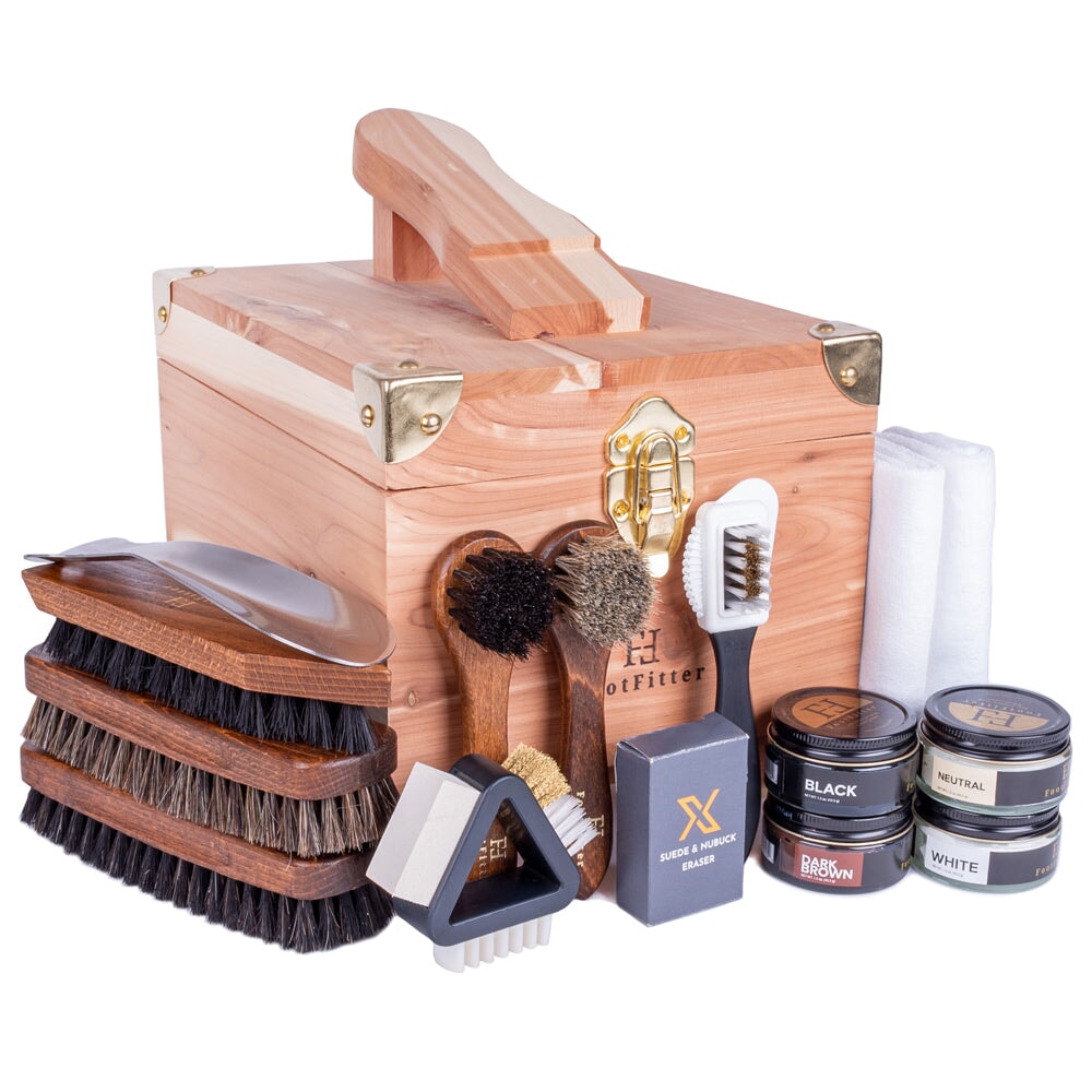 Ręka z szczotką do zamszu delikatnie czyszcząca brudną powierzchnię buta